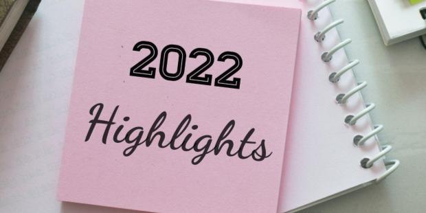 2022 Highlights written on a pink sticky note, surrounded by office supplies