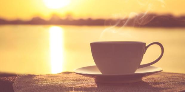 A steaming coffee cup appears with the sunrise in the background